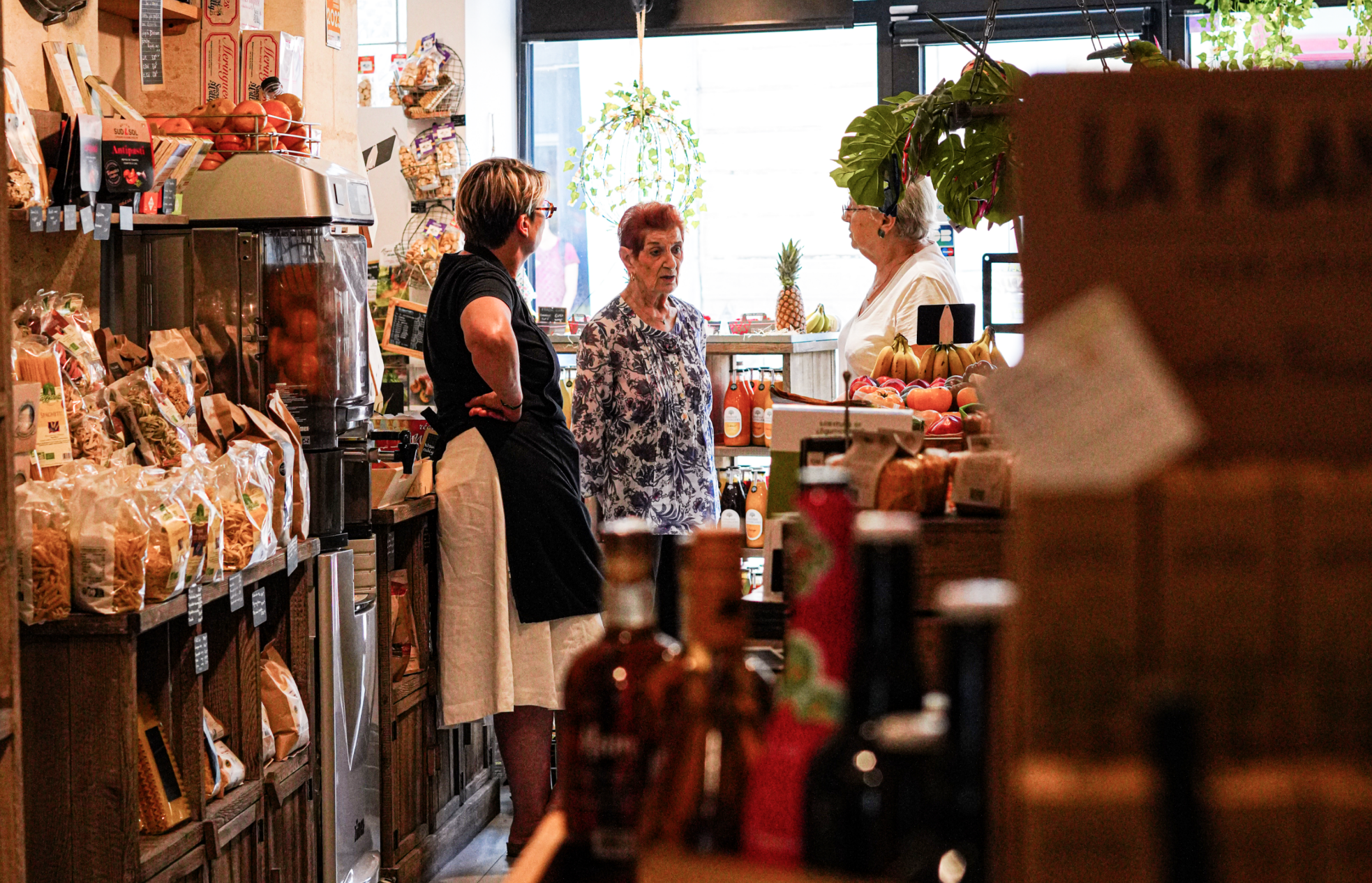 Deux clientes échnagent avec Sonia derrière le comptoir de la boutique du Petit Marché d'Ornano